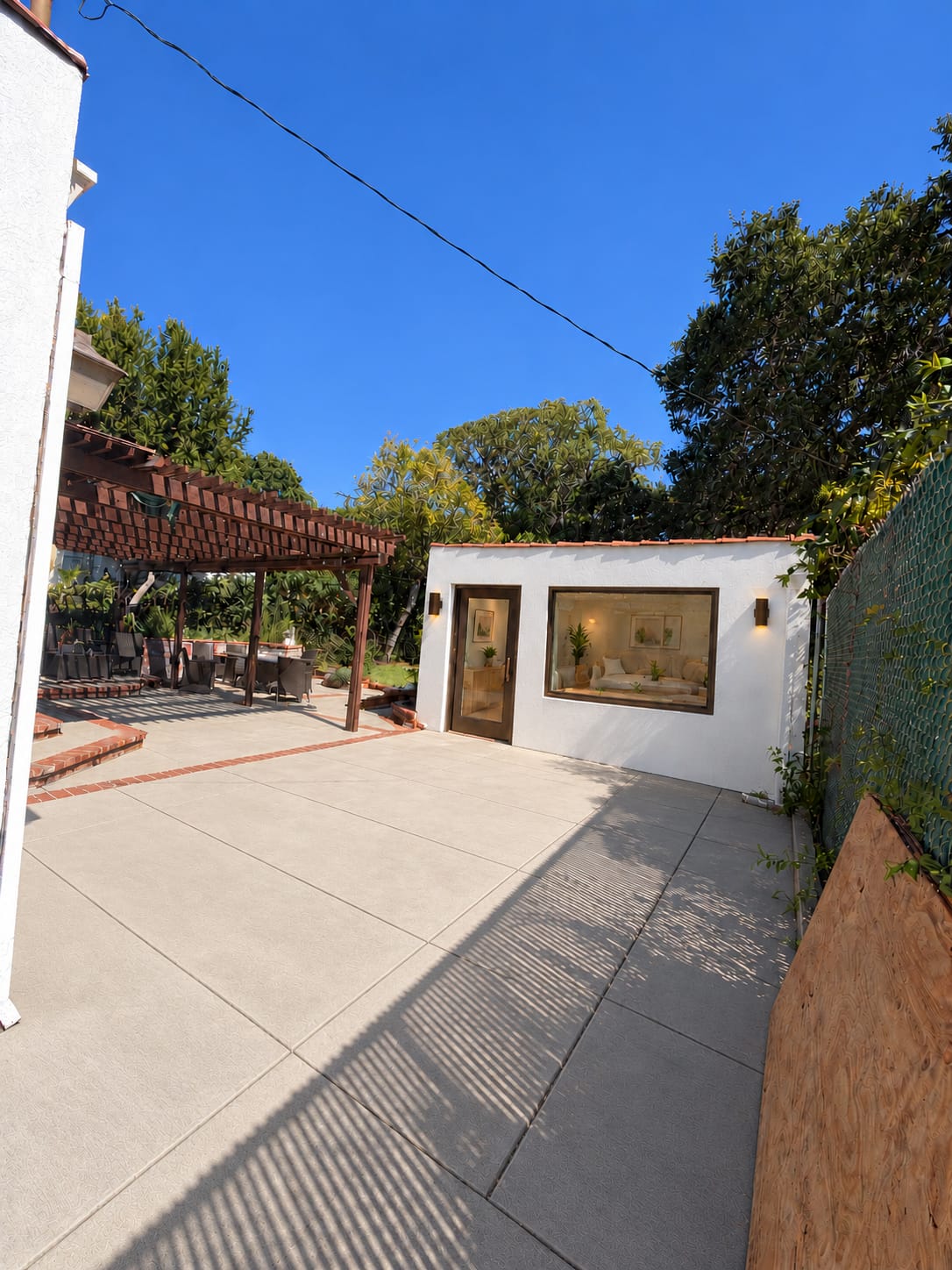 The same garage shown as a small white stucco ADU with a glazed entry door, a living room window and new concrete
